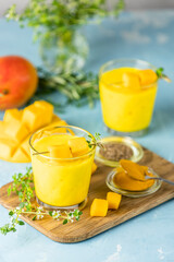 Yellow Indian mango yogurt drink Mango Lassi or smoothie with turmeric and saffron. Healthy probiotic Indian cold summer drink on blue background