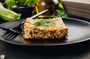 Zucchini casserole on dark background. Dietary, low-calorie, healthy food. Homemade Casserole from squash with chicken and eggs.