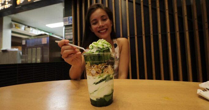 Woman eating matcha ice cream, aka green tea ice cream that is very popular in Japan and a food trend. SLow motion.