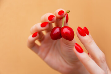 paired ripe cherries in the hands of a girl with red nails