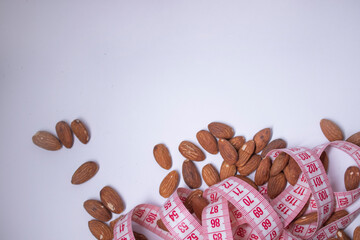 Red measuring tape with almonds . Diet and Healthy life concept. Top view. Copy space. Isolated. White background. High quality photo