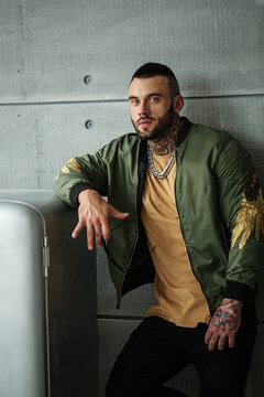 Sexy closeup portrait of elegant handsome male model with fashion tattoo and a black beard standing and posing near Stylish old retro USSR refrigerator in trendy clothes. Professional Studio image.