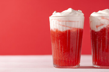 Strawberry smoothie shakes in glass with whipping cream on red background with copy space.Summer refreshing drink mocktail close-up