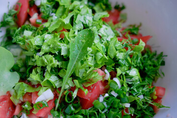 Vegetable salad with fresh lettuce, tomatoes and cucumber in clay pot. Top view.