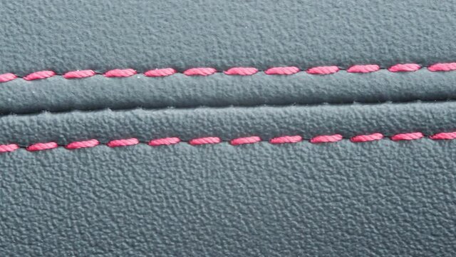 closeup detail of a car interior leather folds stitch red thread.