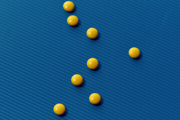 Yellow pills scattered, lying randomly over blue background. Health care and treatment concept.