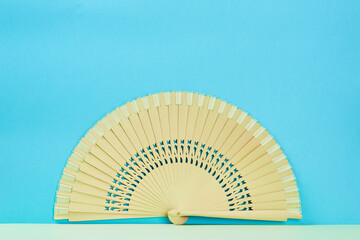 Wooden hand fan isolated on blue background, copy space. Traditional chinese, japanese bamboo accessory, place for text