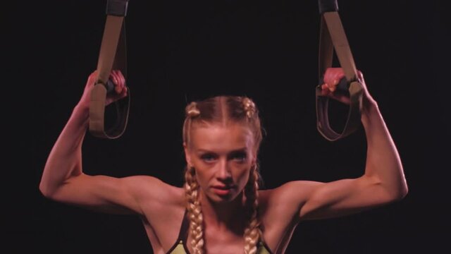 Trainer woman doing inverted row using TRX frontal view. Sports video tutorials isolated on black. Health care concept. Sports concept. tinted footage. Prores 422. 