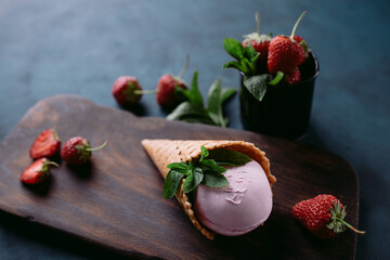 Strawberry ice cream scoop in waffle cone close up. Delicious refreshing seasonal sweets for summer