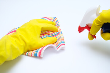 Hands in yellow rubber gloves wiping dust with microfiber cloth and spraying with cleaning agent from a sprayer, cleaning up the house concept, white background