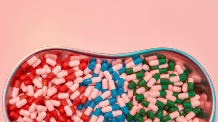 Creative flat lay, top view of different pills, capsules lying in metal box on a pastel pink background. Health care, vitamins and treatment concept