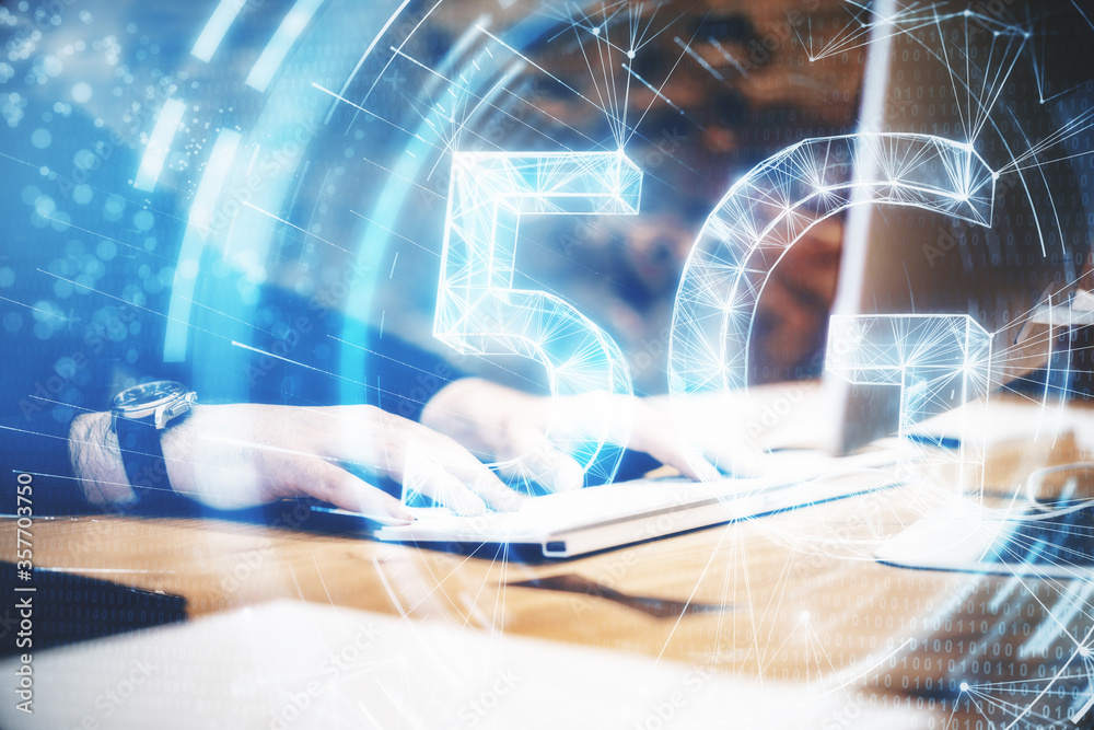 Leinwandbilder Hands using keyboard on desktop with abstract 5G network hologram.