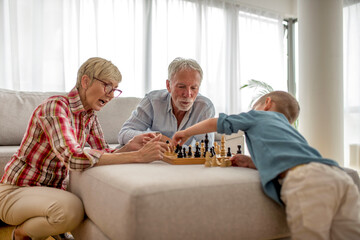 Grandparents and grandson playing chess together at home
