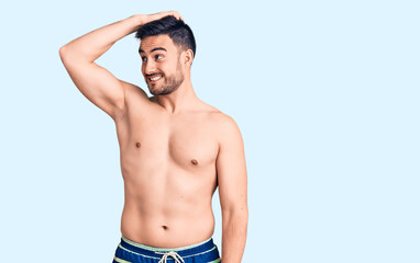 Fototapeta premium Young handsome man wearing swimwear smiling confident touching hair with hand up gesture, posing attractive and fashionable