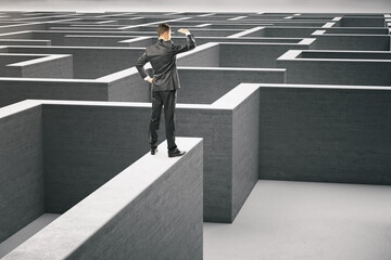 Businessman in suit standing on gray concrete labyrinth.