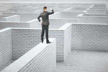 Young businessman standing on white brick labyrinth.