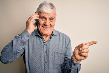 Senior hoary man having conversation talking on the smartphone over white background very happy pointing with hand and finger to the side