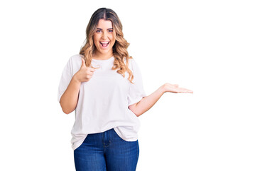 Young caucasian woman wearing casual clothes showing palm hand and doing ok gesture with thumbs up, smiling happy and cheerful