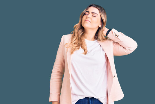 Young caucasian woman wearing business clothes suffering of neck ache injury, touching neck with hand, muscular pain