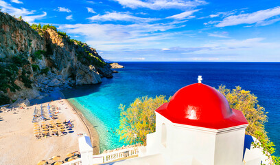 Karpathos Greece Kyra Panagia beach. Red dome church and turquoise sea view. Greek island Dodecanese. Traditional architecture. Scenic coast landscape. No people. 8K © Freesurf