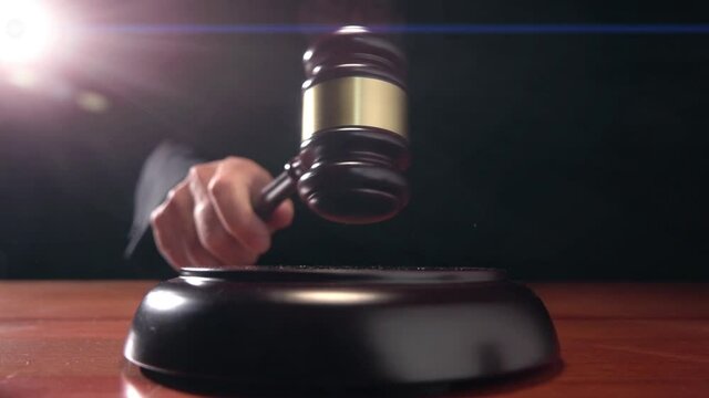 Judge hitting Gavel off a block in courtroom, dark background slow motion dolly shot