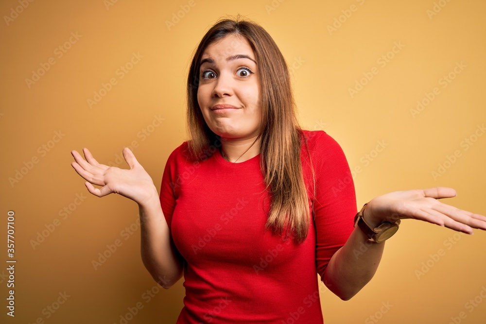 Sticker beautiful young woman wearing casual red t-shirt over yellow isolated background clueless and confus