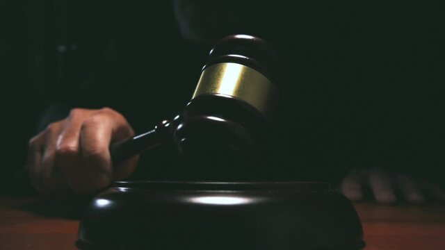 Judge hitting Gavel off a block in courtroom, dark background slow motion dolly shot