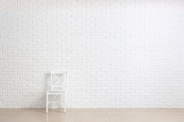 Chair near white brick wall in room
