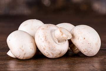 Several fresh mushrooms champignon on wooden table.