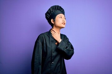 Young beautiful chinese chef woman wearing cooker uniform and hat over purple background Touching painful neck, sore throat for flu, clod and infection