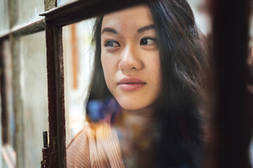 young asian woman portrait feeling lonely behind window