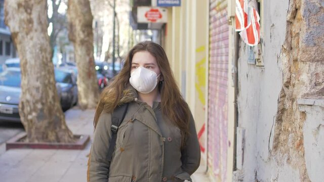 Portrait of a young student woman wearing protective mask on street. Concept of health and safety life, N1H1 coronavirus, virus protection, pandemic in china. She is affraid in a loneless street. 