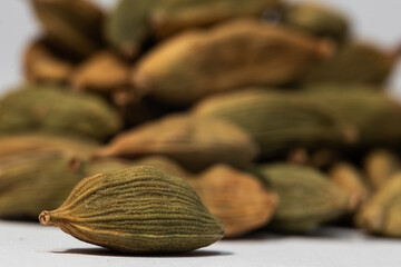 A macro shot of a cardamon cardamom pod in front of a pile