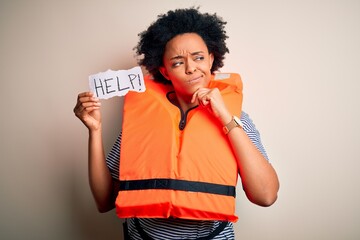 Young African American afro woman with curly hair wearing lifejacket holding help paper serious...