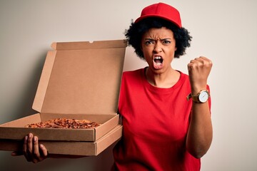 Young African American afro delivery woman with curly hair holding box with Italian pizza annoyed and frustrated shouting with anger, crazy and yelling with raised hand, anger concept