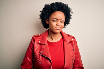 Fototapeta na wymiar Young beautiful African American afro woman with curly hair wearing casual red jacket with hand on stomach because indigestion, painful illness feeling unwell. Ache concept.