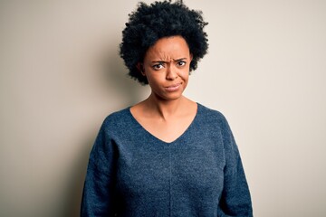 Young beautiful African American afro woman with curly hair wearing casual sweater skeptic and nervous, frowning upset because of problem. Negative person.