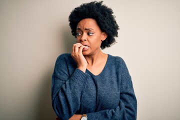 Young beautiful African American afro woman with curly hair wearing casual sweater looking stressed...