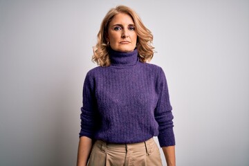Middle age beautiful blonde woman wearing purple turtleneck sweater over white background with...