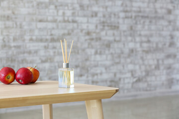 Reed diffuser and apples on table in room