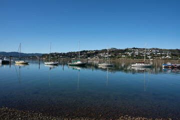 View of yachts and boats reflecting in the water docked in Porirua near Wellington New Zealand on a calm sunny day