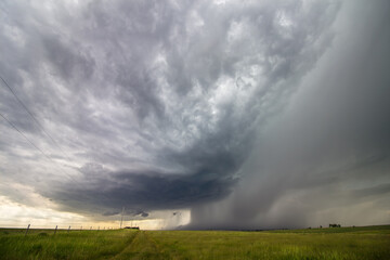 Fototapeta na wymiar A supercell thunderstorm approaches over the rural countryside, with curtains of rain and hail falling.