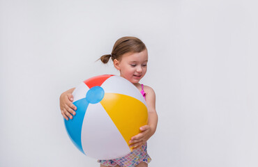 A little girl in a swimsuit with an inflatable ball on a white isolated background with space for text. Looking down