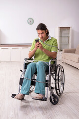 Young male invalid in wheel-chair suffering at home