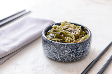 Fototapeta na wymiar Bowl with tasty seaweed on light background