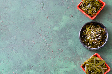 Bowls with tasty seaweed on color background