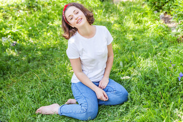 Happy girl smiling outdoor. Beautiful young brunete woman with brown hair resting on park or garden green grass background. European woman. Positive human emotion facial expression body language.