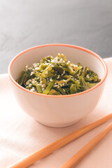 Bowl with tasty seaweed and chopsticks on table
