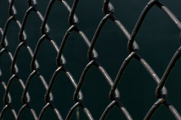 Fototapeta premium Metal fence wire mesh on dark background