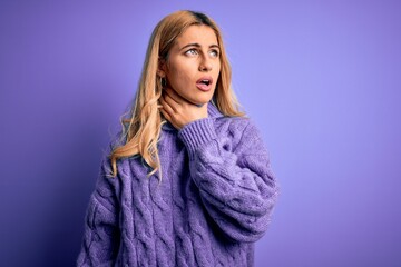 Young beautiful blonde woman wearing casual turtleneck sweater over purple background Touching painful neck, sore throat for flu, clod and infection
